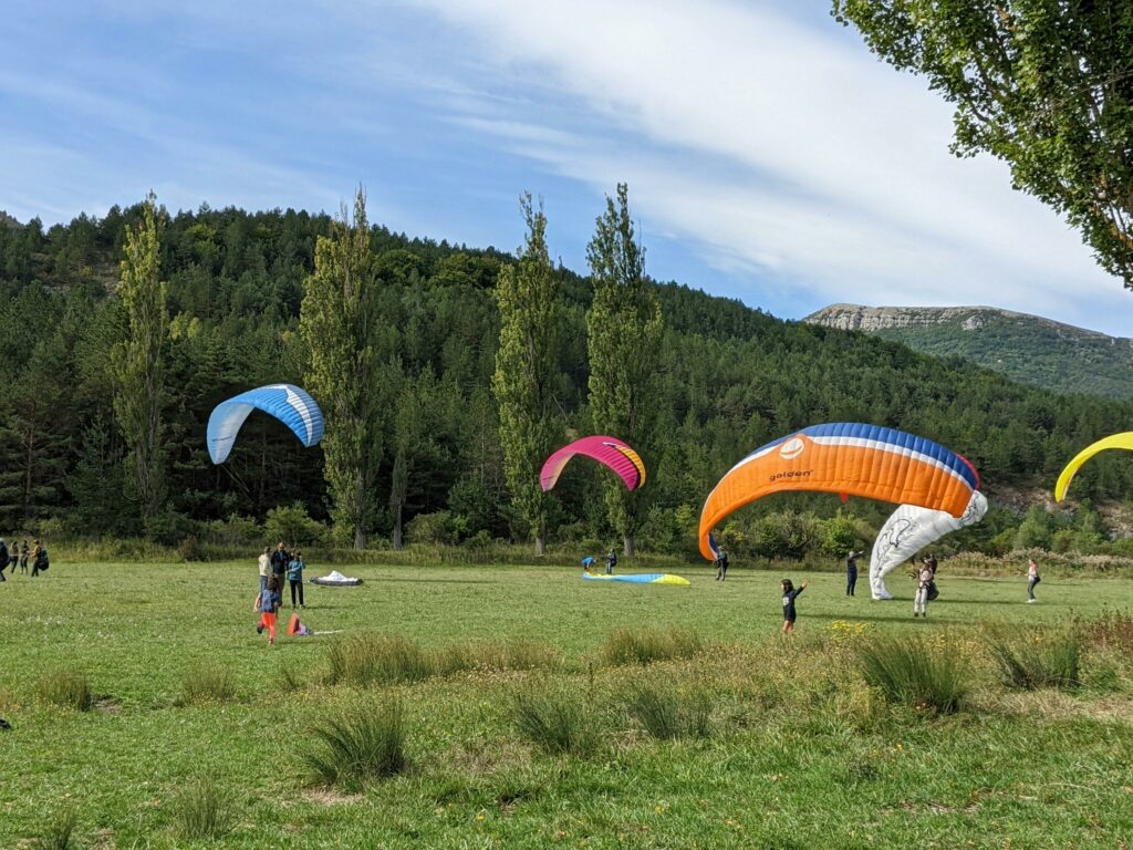A group of people enjoying paragliding in a scenic outdoor landscape under clear skies.
