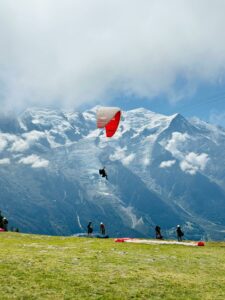 A paraglider soars over the French Alps amidst stunning snow-capped mountains.
